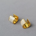 Dettaglio macro di orecchini a cerchio in ottone dorato con intarsio in smalto perlato - Bianco Sporco