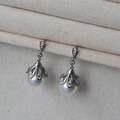Close-up of pearl drop earrings with sparkling zircon crown settings on jewelry display - Pearl Stud Earrings