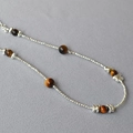 Dettaglio ravvicinato di perle occhio di tigre e perline d'argento su collana doppia - Stile con Perline Occhio di Tigre