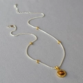 Dettaglio di una collana vintage a doppio strato con occhio di tigre su tessuto grigio - Stile Pendente a Catena
