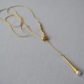 Vista dettagliata della collana lunga dorata con accenti metallici irregolari e perla - Oro