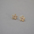 Détail macro de boucles d'oreilles étoiles dorées avec incrustation blanche et gemme rouge - Boucles d'Oreilles Clous Étoile Zircone Rouge