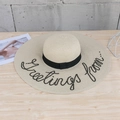 Chic wide brim straw sun hat with black ribbon and Greetins from embroidery for beach trips - M / Beige