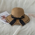 Elegant wide brim straw hat with black bow ribbon and fashion accessories on white fabric - Khaki