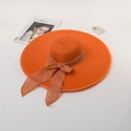 Detail of orange straw hat with a wide brim and elegant brown bow tie accent - M (56-58cm) / Orange