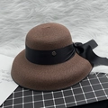Detail of elegant straw hat with black satin ribbon bow and gold metal M logo badge - M / Coffee