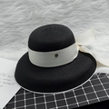 Elegant black straw sun hat with creamy ribbon and stylish bow in a chic setting - M / Black