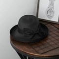 Detail eines eleganten schwarzen Strohhuts mit großer Schleife auf Holzoberfläche - M (56-58cm) / Schwarz