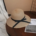 Close-up of woven straw sun hat with black ribbon bow on a rustic wooden table - M (56-58cm) / Khaki