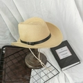 Detail of a straw cowboy hat with a leather band and wind rope on a wooden stand - M / Beige