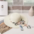 Detalle de sombrero de paja con adornos de perlas y cinta de seda con flores frescas - M / crema