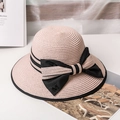 Detail of pink straw sun hat with black bow and metallic M letter charm on white desk - M / Pink