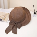 Detail shot of a dark brown woven straw hat with a large bow and frayed edge on white desk - M (56-58cm) / Coffee