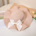 Detail of pink straw sun hat with wavy brim and white satin ribbon bow decoration - M / Nude Pink