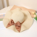 Close-up of beige woven straw hat with a large brown satin bow and elegant wavy brim - M / Beige