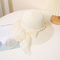 Détail d'un chapeau de paille beige avec un nœud en tulle et des perles élégantes - M / crème