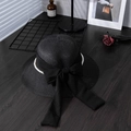 Detalle de un sombrero de paja negro con lazo y perlas sobre una mesa de madera oscura - M / Negro