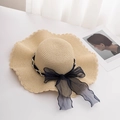 Close-up of beige straw sun hat featuring a wide wavy brim with pearls and black ribbon - M (56-58cm) / Beige