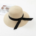 Détail d'un chapeau de paille beige clair avec ruban noir élégant sur tissu gaufré - M / Beige