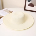 Detail of a wide-brimmed cream straw hat with spiral woven texture on a flat surface - M (56-58cm) / Milk White