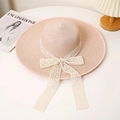 Detalle de sombrero de paja rosa con ala ancha y lazo de encaje blanco en un escritorio - M / Rosa Carne