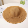 Close-up of hand-woven straw hat with frayed edges and decorative bow detail - M / Khaki