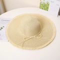 Detail of beige straw hat featuring frayed edges, a delicate bow, and wide sun brim - M / Beige