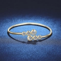 Anillo abierto dorado pulido con seis gemas redondas graduadas sobre un fondo oscuro - 1.8ct Moissanita Dorado