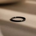 Macro shot of minimalist matte black stainless steel ring on a textured neutral surface - US7 / Black
