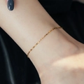 Minimalist gold plated stainless steel lace anklet shown on skin with black background - Lips Chain Anklet / Gold