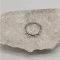 Detalle de anillo plateado ondulado con cuatro perlas blancas de diseño moderno - Color Acero