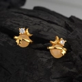 Elegante goldene Saturn Ohrstecker mit weißem Achat und Zirkonia auf schwarzem Holz - 18K Gold
