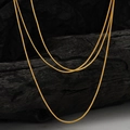 Elegante goldene Schlangenkette in verschiedenen Längen auf dunklem Holzdekor - 925er Silber / Altgold