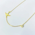 Macro detail of gold swallow pendant with single sparkling stone on minimalist chain - Full 925 Sterling Silver / Gold