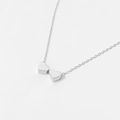 Macro shot of silver dual heart-shaped pendant on a minimalist fine cross chain - Double Heart White Gold