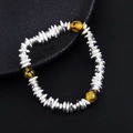 Detail of silver disc beads bracelet with three tiger eye stone accents on black background - Tiger Eye Style