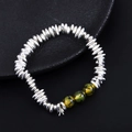 Detailed macro shot of silver beads and green hematite stone bracelet on black display - Green Agate Style