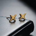 Minimalist polished golden star stud earrings displayed on a black leather surface - Cross Star Stud Earrings / Gold (X118-B)
