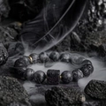 Pulsera artesanal de piedra volcánica con detalles dorados sobre fondo de roca negra - Estilo Piedra de Lava (S154-A)