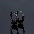 Détail de boucles d'oreilles noires géométriques avec trois anneaux sur fond sombre - Noir