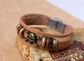 Dettaglio del bracciale multistrato in pelle marrone con teschio dorato e perline - Cuoio