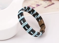 Detalle de una pulsera de cuero negro tejida a mano con cordón azul y blanco y hebilla bronce - Cordón Azul y Blanco