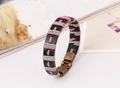Detalle de pulsera de cuero negro trenzado con cordones rosa y verde y cierre de bronce - Cordón Ciruela y Verde