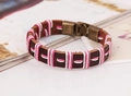 Primer plano de pulsera de cuero trenzado con cordones rosa y blanco y cierre de bronce - Cordón Ciruela y Blanco