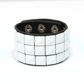 Nahaufnahme von drei Reihen weißer Pyramidennieten auf einem schwarzen Punk-Lederarmband - Weiß