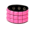 Detail eines Punk-Lederarmbandes mit drei Reihen neonpinker quadratischer Pyramidennieten - Rosa