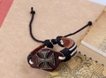 Gros plan sur un bracelet en cuir marron avec croix de fer bronze et détails tressés - Iron Cross
