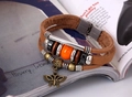 Detail of bohemian leather bracelet featuring butterfly charm and multi-layered beads - Tan