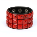 Detail eines Punk-Lederarmbands mit roten Pyramidennieten und schwarzer Farbspritzer-Textur - Rot