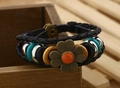 Dettaglio di bracciale bohémien multistrato in pelle con fiore di bronzo e perline turchesi - Fiore Arancione Rosso